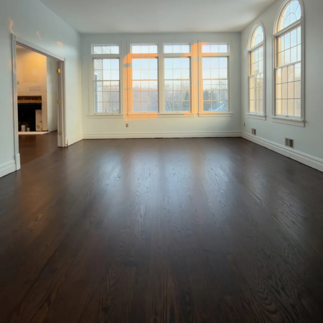 Empty room with newly refinished dark hardwood floors.